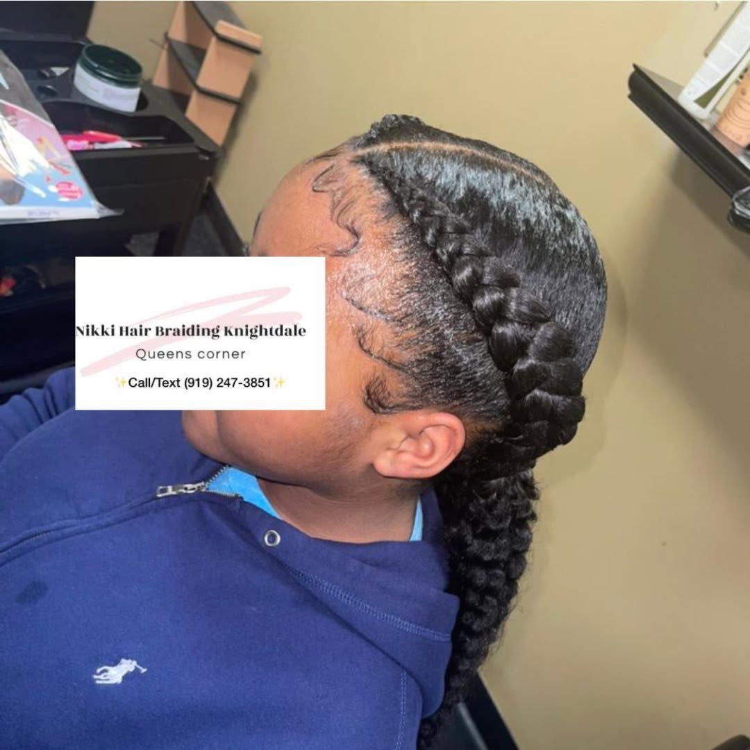 Person wearing blue shirt displaying long braided hairstyle in indoor salon setting