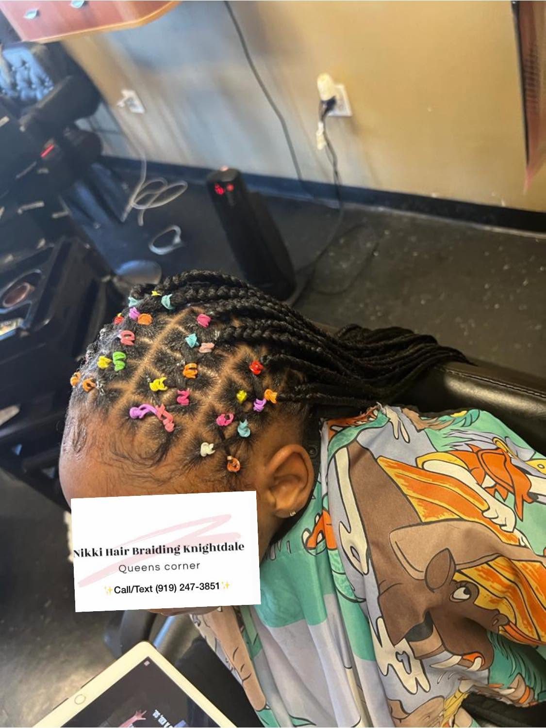 Child's braided hairstyle with colorful beads, business card for Nikki Hair Braiding visible