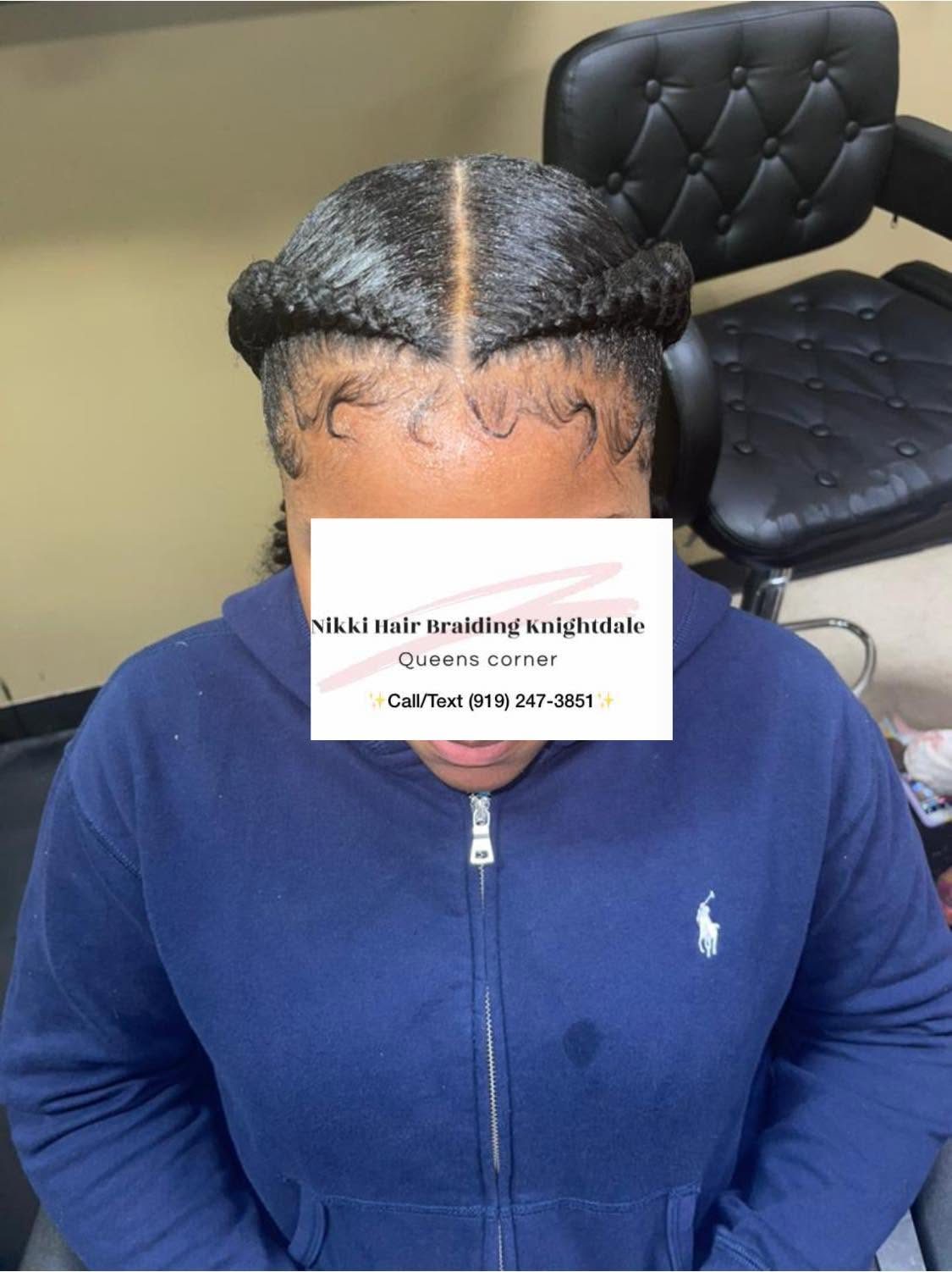 Back view of woman with braided hairstyle featuring buns and center part in salon chair