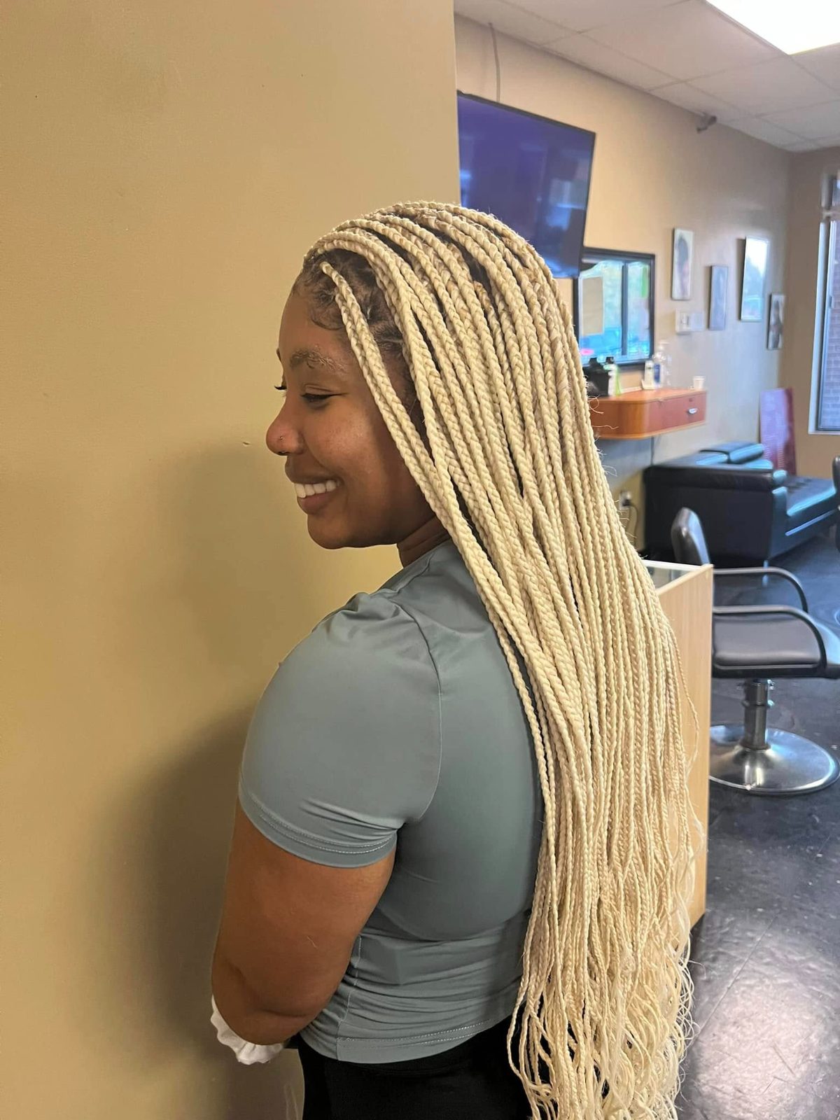 Woman with long blonde braids smiling in a salon interior