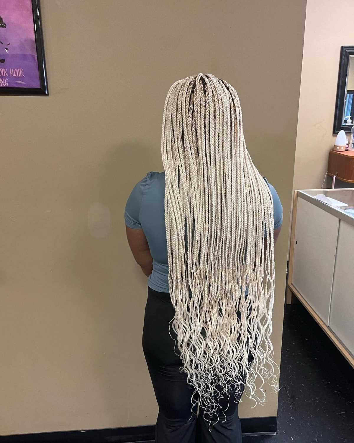 Woman with long blonde box braids viewed from behind in a salon