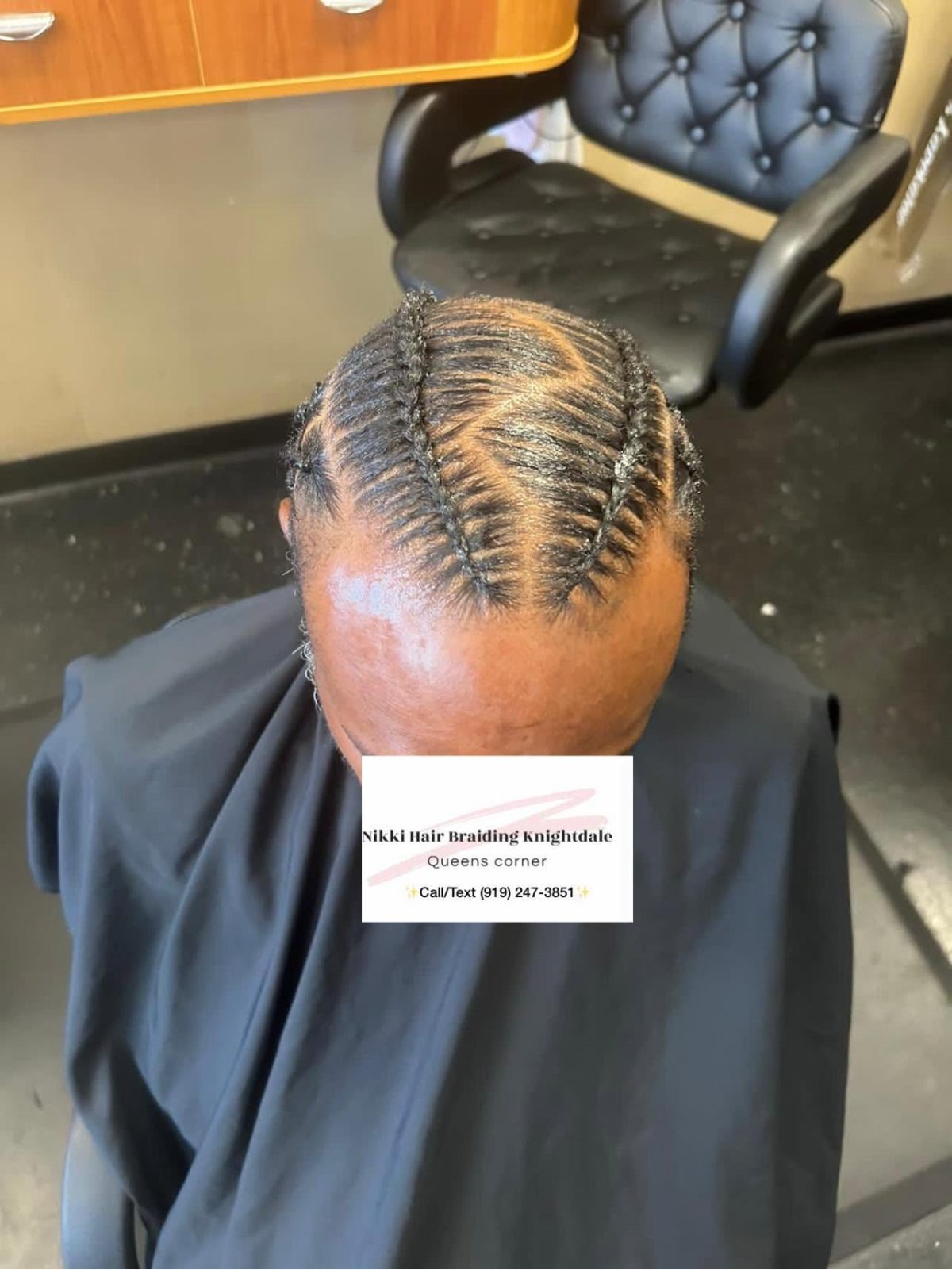 Overhead view of intricate cornrow braids styled on a client's head in a salon setting