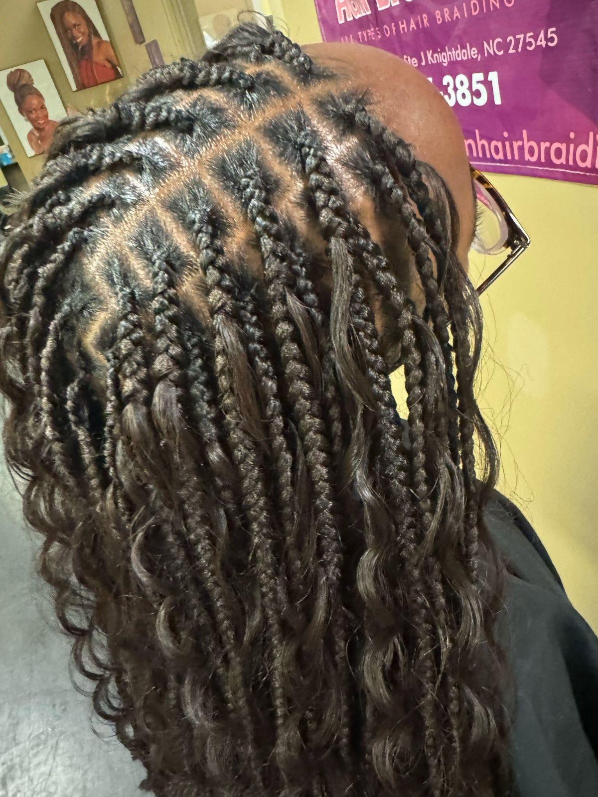 Back view of long braided hair with wavy ends in a salon setting