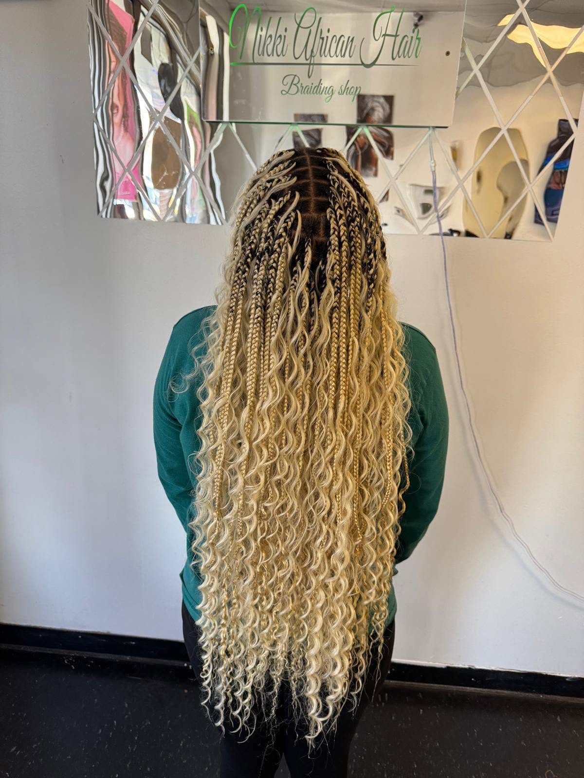 Woman displaying long blonde box braids with curled ends at Ailebi African Hair Braiding salon