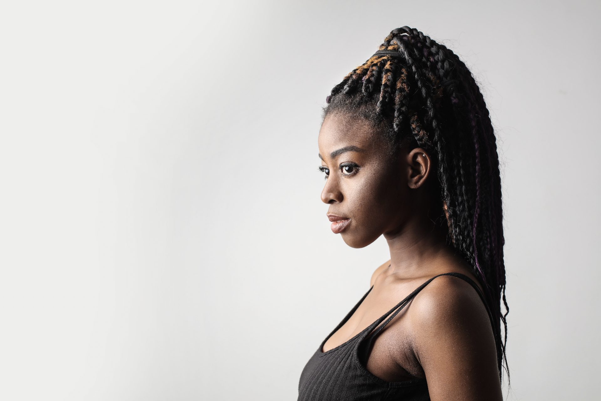 Professional portrait of woman in profile wearing black tank top with braided hairstyle
