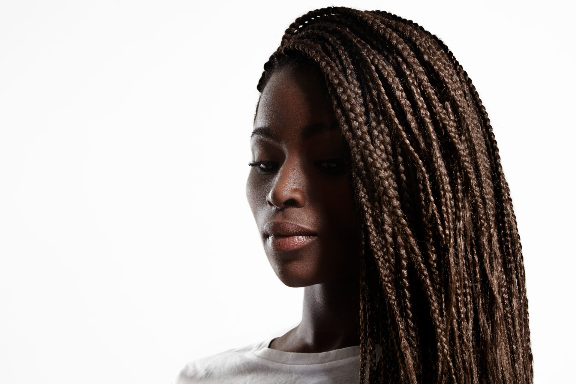 Woman with brown braided hair in profile view against white background