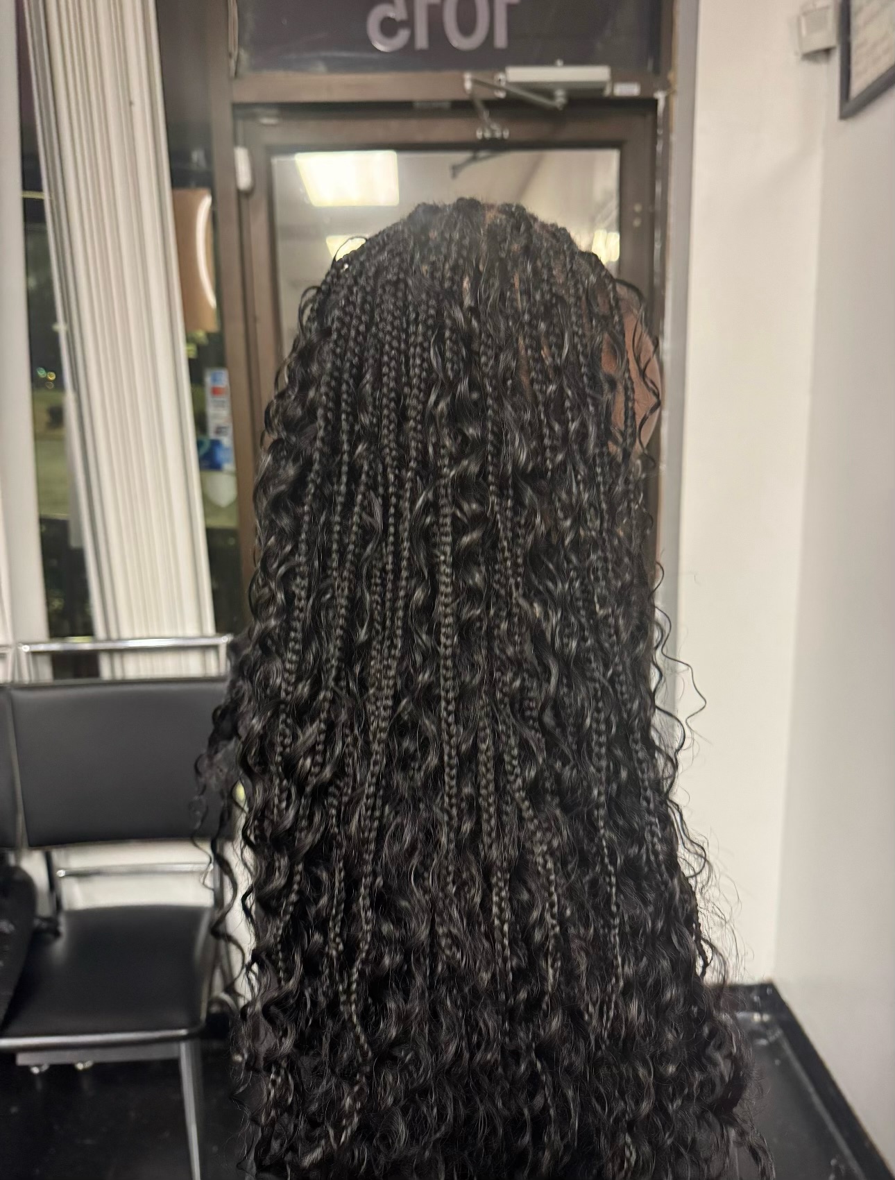 Back view of long braided black hair with curled ends in a salon setting