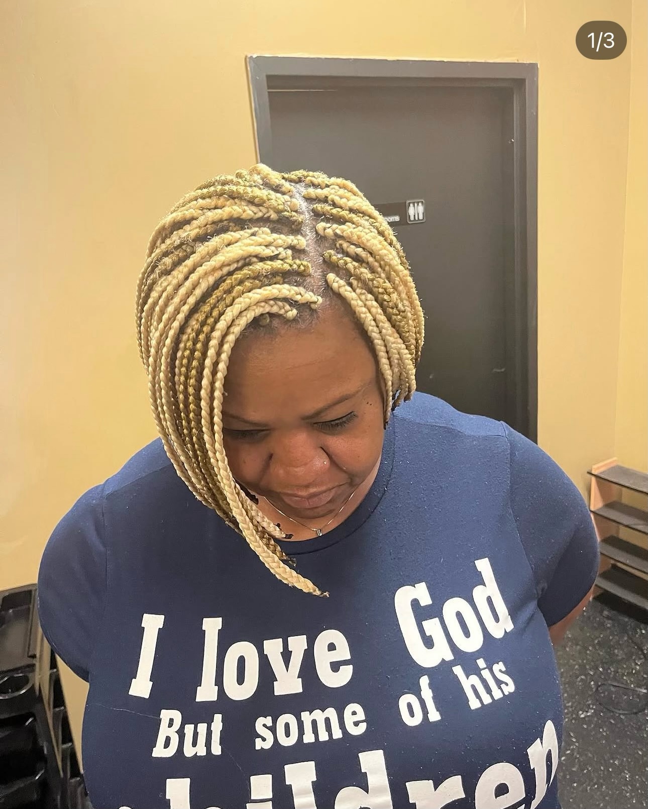 Woman wearing blonde braids and navy blue shirt in indoor setting