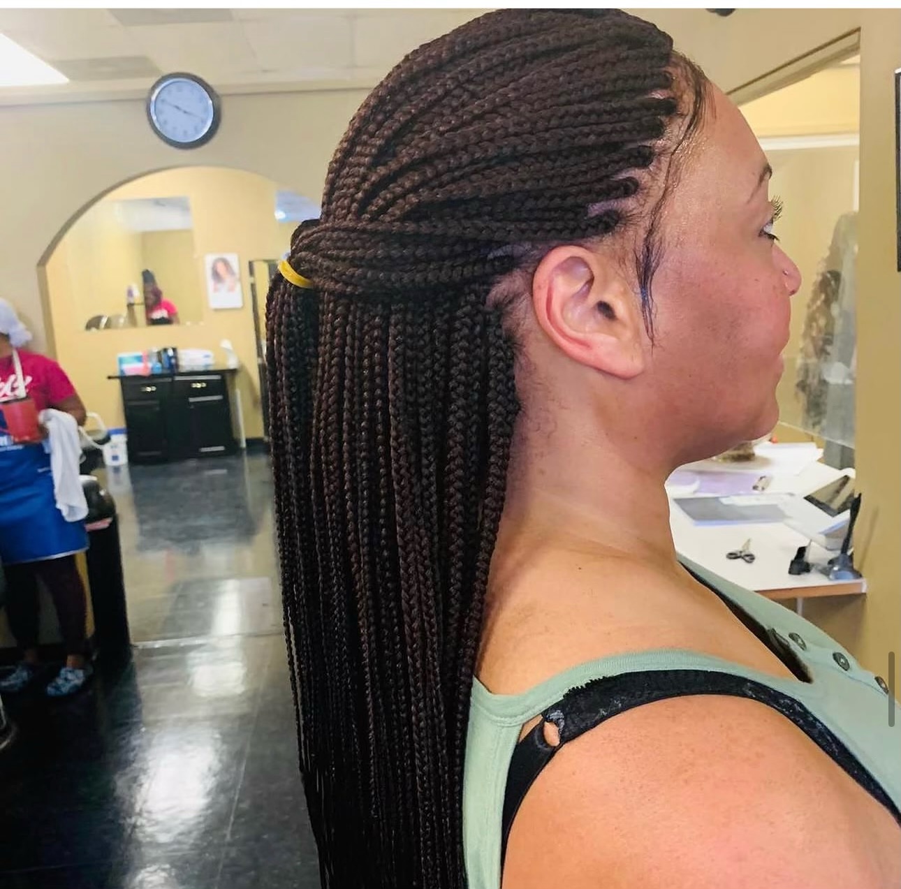 Woman with long box braids in a salon, shown in profile view