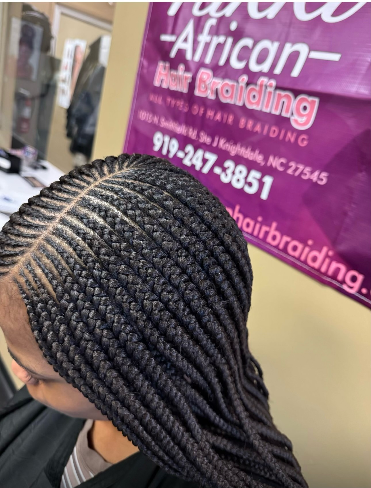 Close-up of African braids hairstyle in salon with purple signage visible
