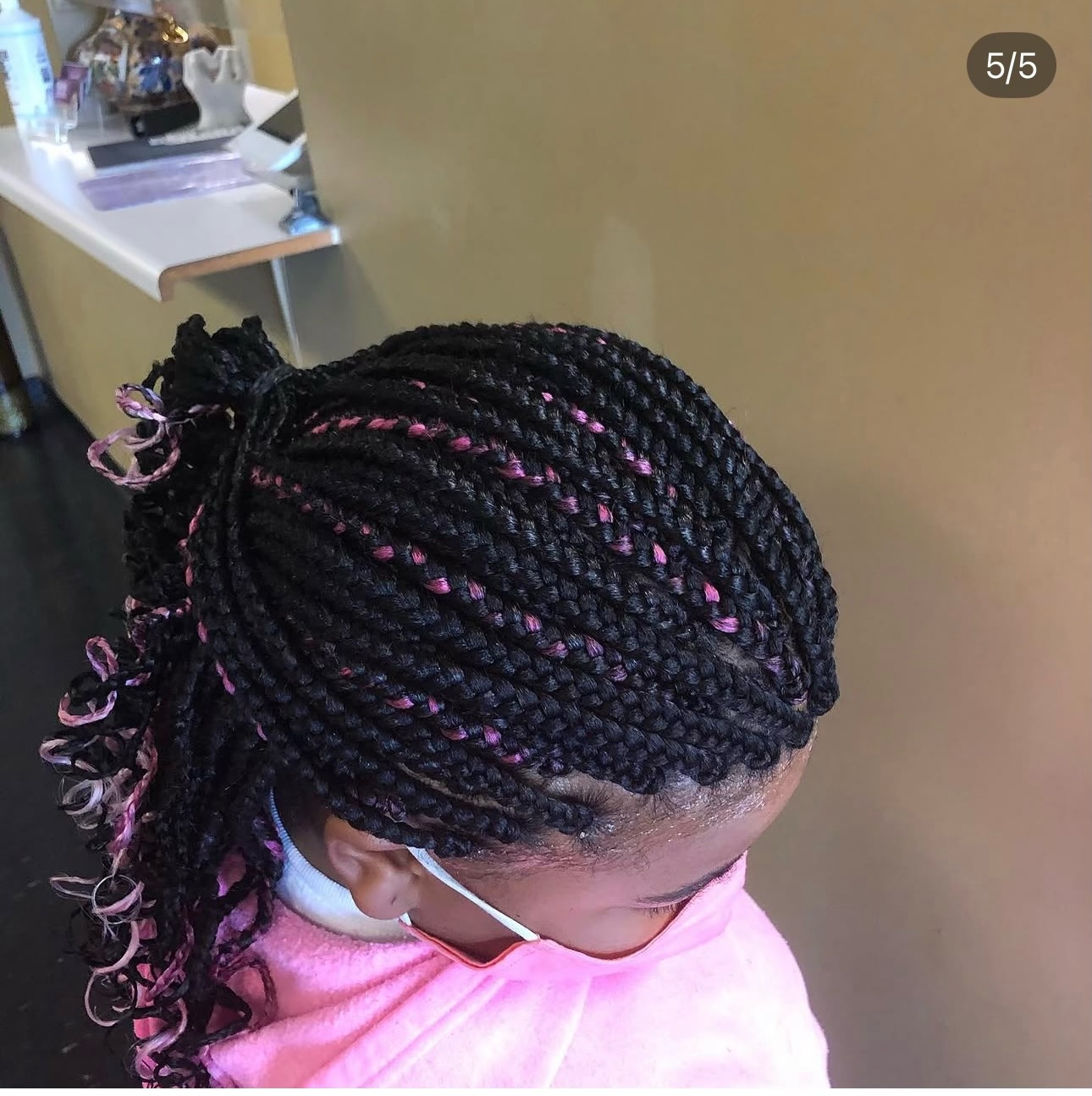 Black braids with pink thread detail pulled into a curled ponytail