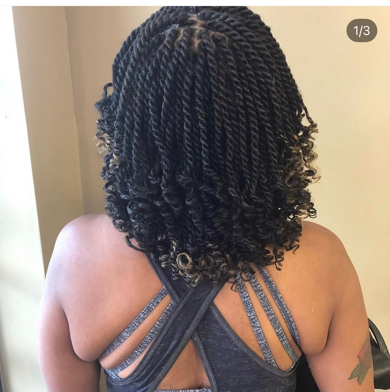 Back view of long black twisted braids with curled ends and highlights