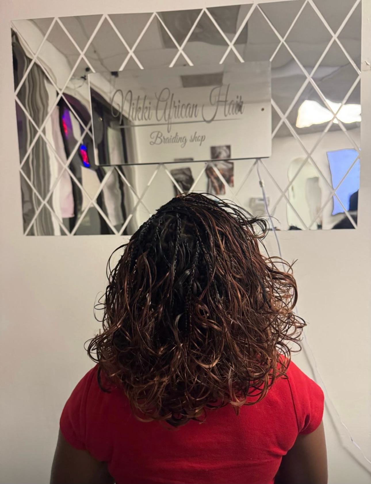 Woman with long wavy brown hair viewed from behind at Mikki African Hair braiding shop