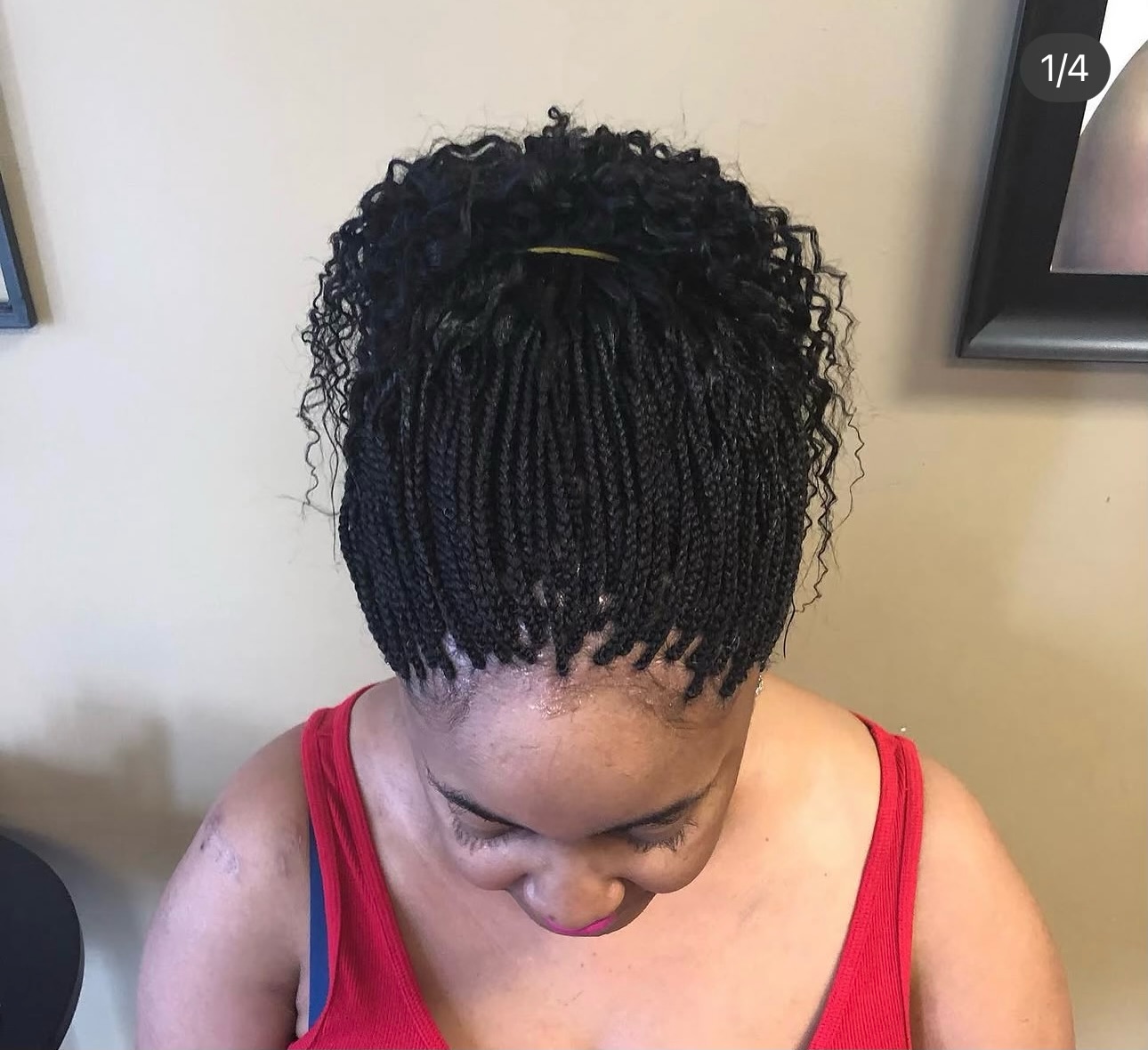 Woman with black box braids styled in an updo with gold hair clip, wearing red tank top