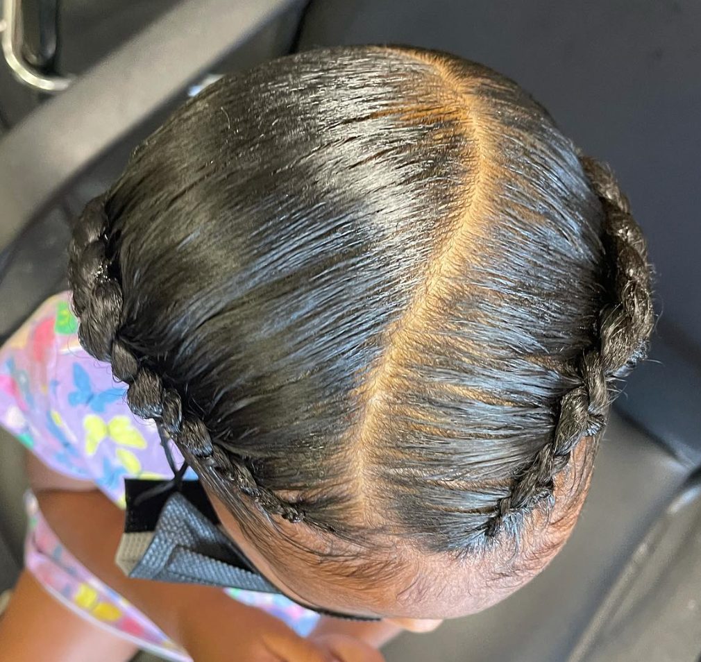 Back view of person with long dark hair styled in braided updo with metallic gold finish