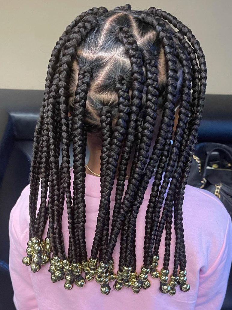 Back view of long box braids with gold ball beads at the ends on person wearing pink shirt