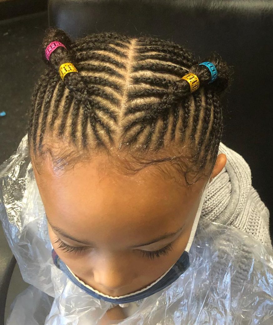 Child with braided hairstyle adorned with colorful hair cuffs in pink, yellow, and blue