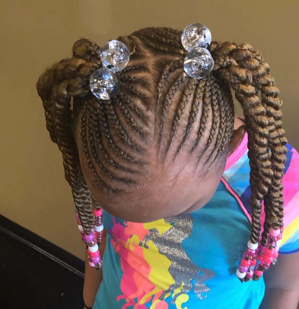 Child wearing colorful shirt with braided hair styled in buns with clear beaded hair clips
