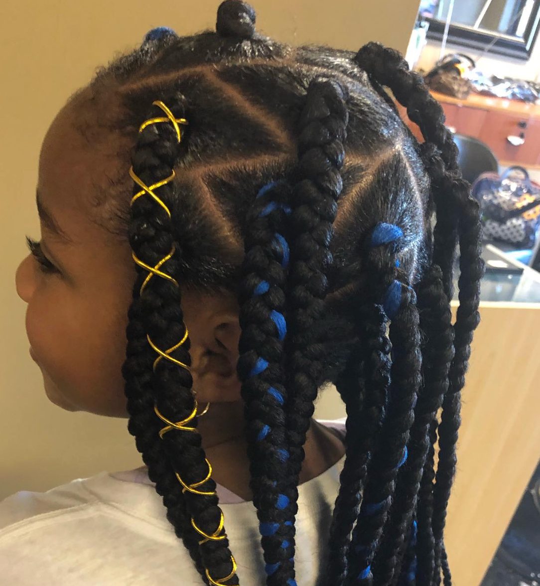 Child with black braided hairstyle adorned with gold and blue hair clips