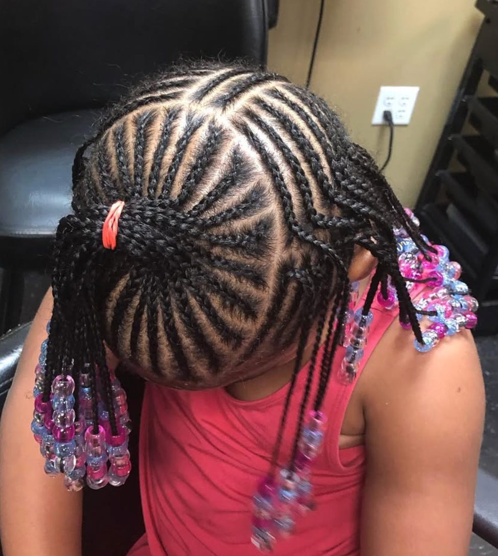 Child with braided hairstyle adorned with colorful beads wearing red shirt